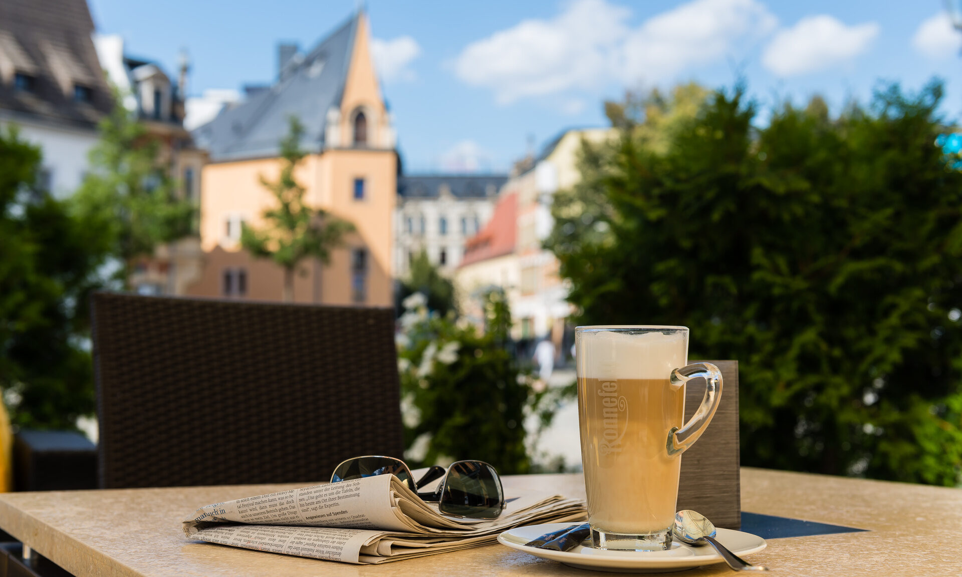 Auf einem Tisch steht eine Tasse Kaffee neben einer Zeitung