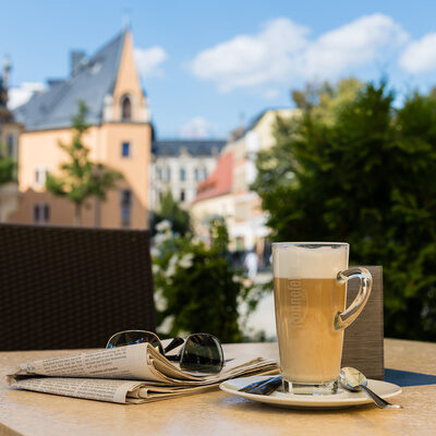 Auf einem Tisch steht eine Tasse Kaffee neben einer Zeitung