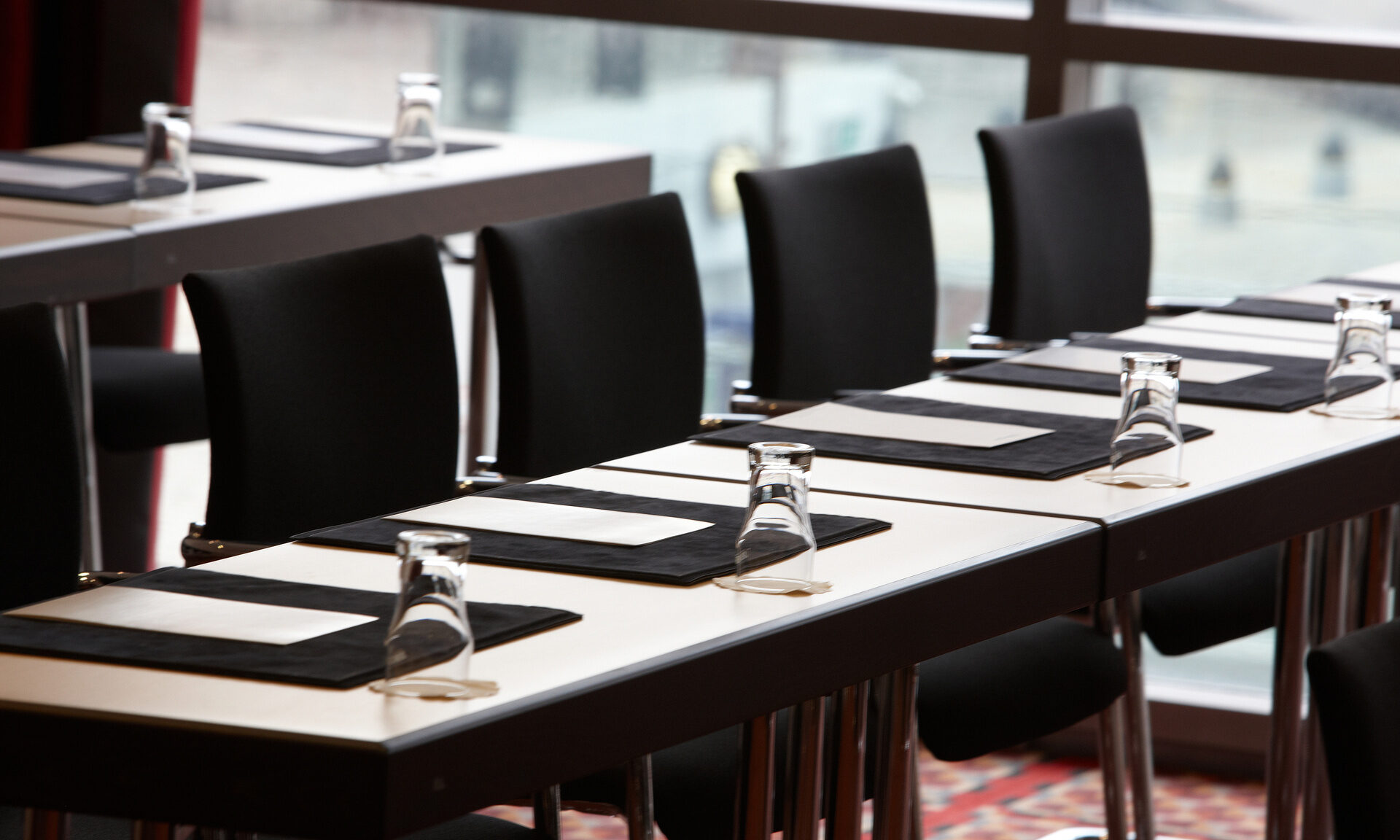 Mehrere Konferenztische sind mit Gl&auml;sern gedeckt