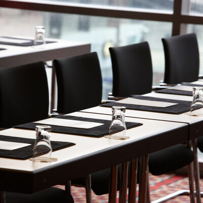 Mehrere Konferenztische sind mit Gläsern gedeckt