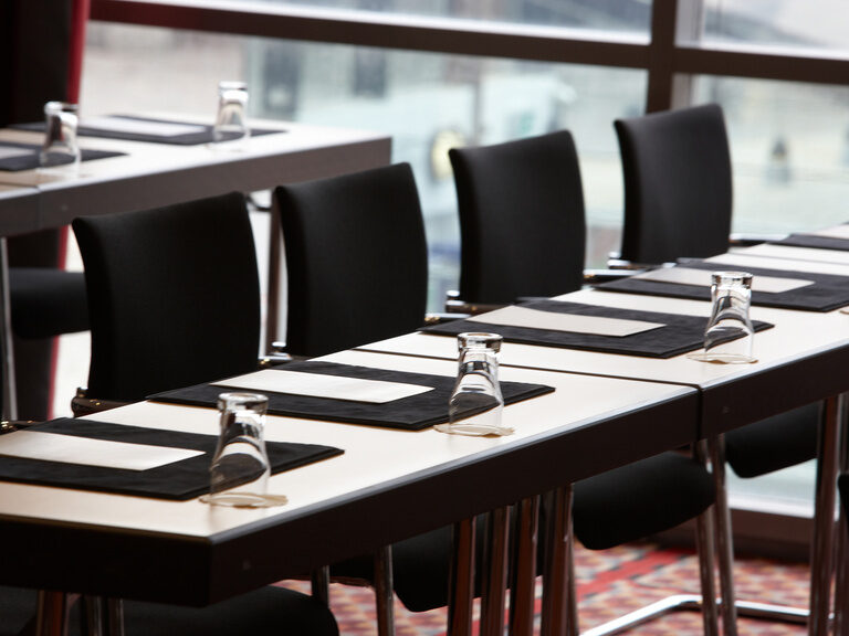 Mehrere Konferenztische sind mit Gläsern gedeckt
