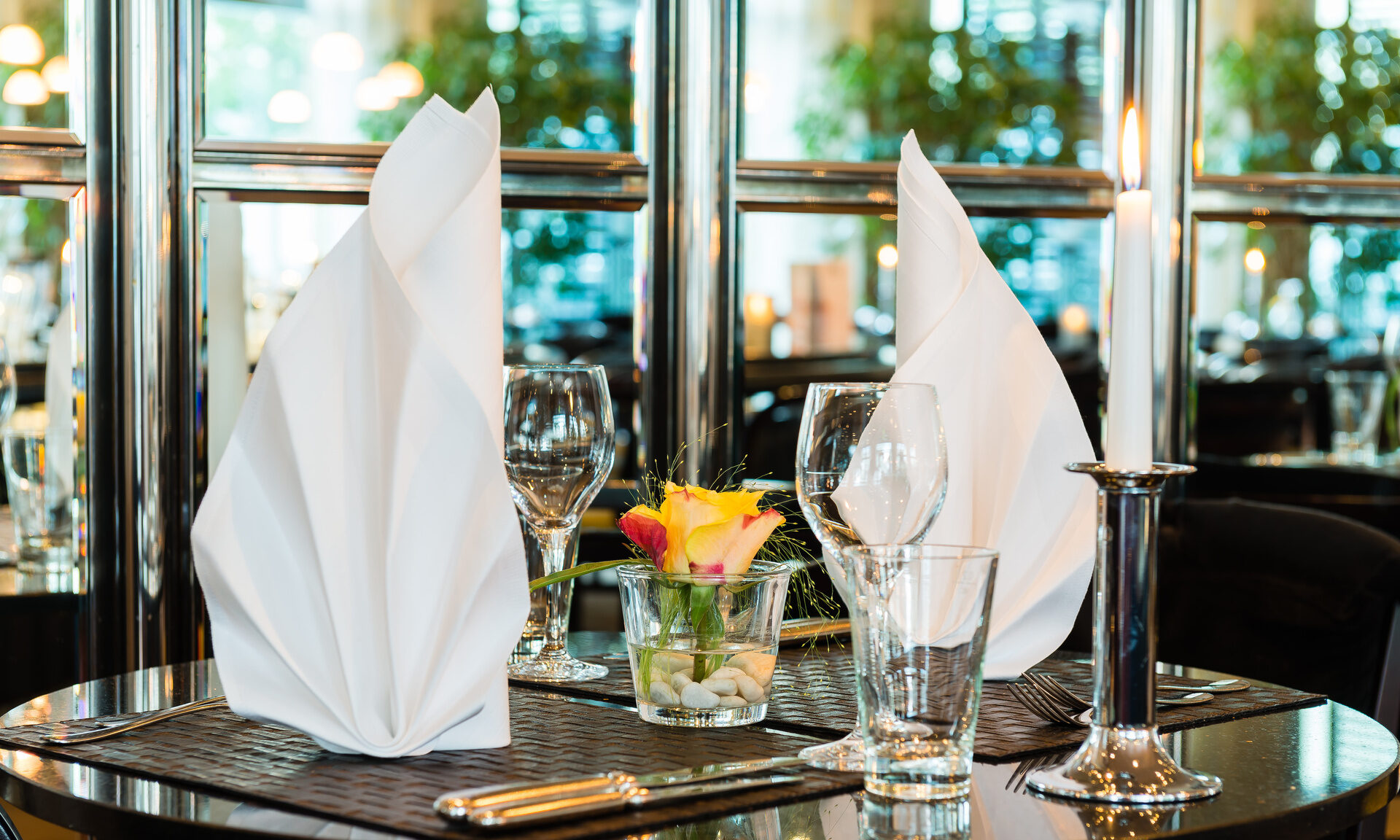 Auf einem schwarzen Tisch ist eine weiße Serviette kunstvoll gefaltet.